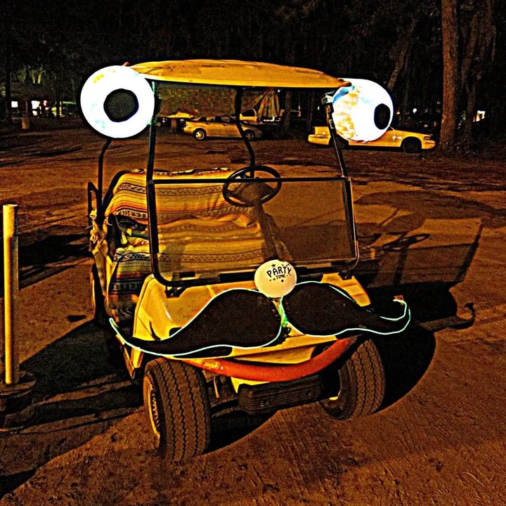 An early Zerble at night at a Suwannee festival, glowing eyeballs on the roof corners, a black mustache outlined in EL wire, and a PARTY TIME balloon for a nose.