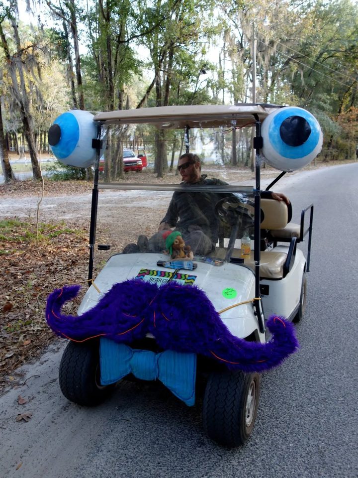 Zerble at Bear Creek in November 2014: a white golf cart with blue eyeballs on the roof corners, a fuzzy purple mustache traced in EL wire, and a big blue bow tie on the front.